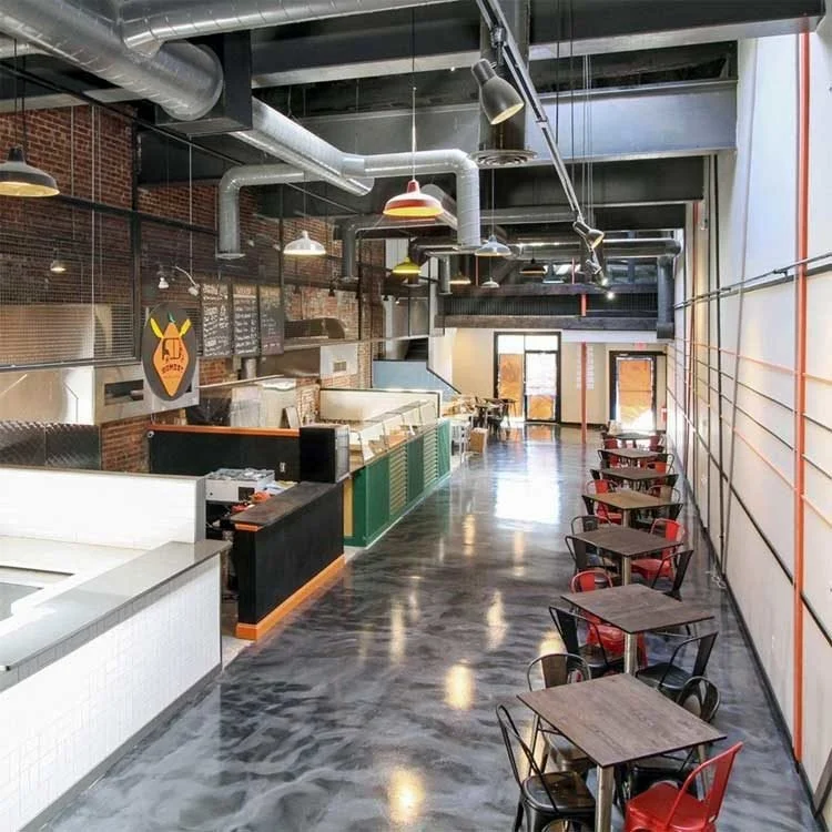 Modern cafe interior with exposed ductwork, wooden tables, brick walls and a seamless resinous floor.
