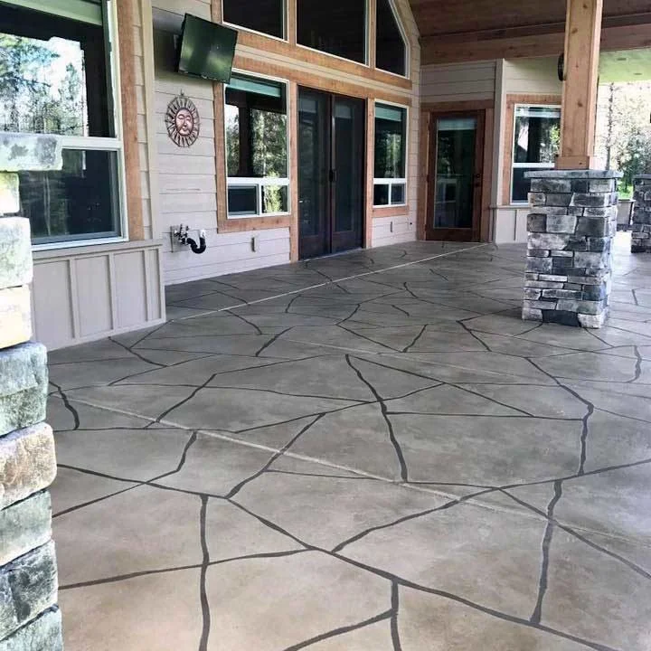 Outdoor covered patio with a flagstone-look thin finish overlay, stone columns and a wooded view.