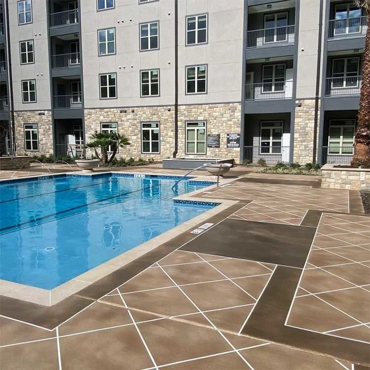 Outdoor apartment pool area with geometric patterned concrete decking, lounge chairs and planters.