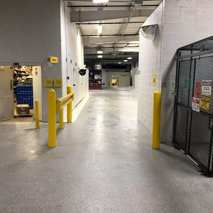 Industrial cold storage corridor with yellow safety bollards and a seamless coated floor.