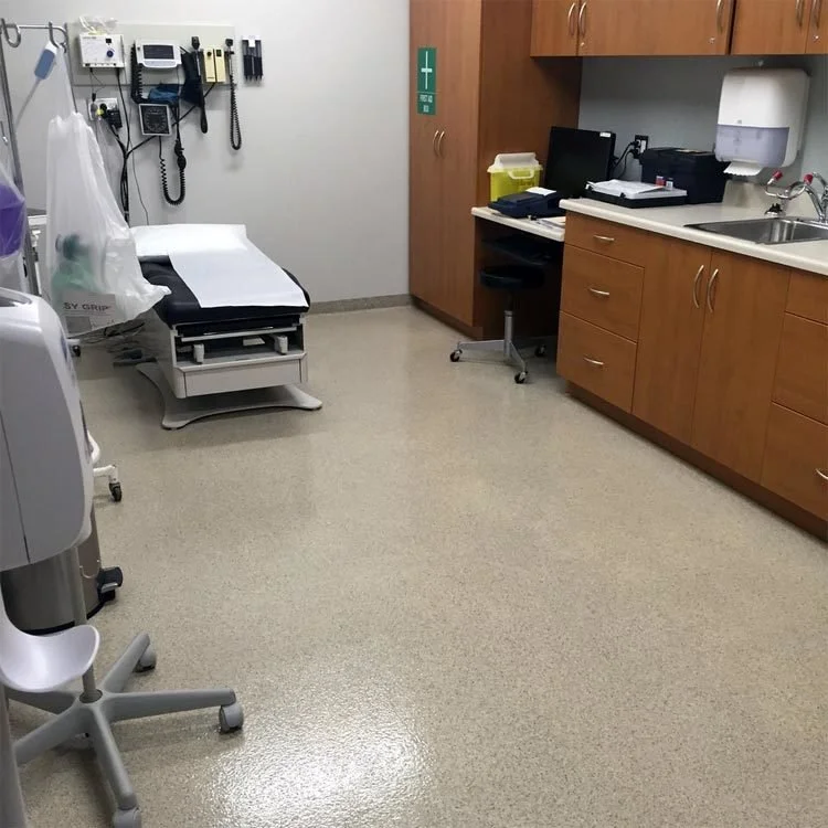 Medical examination room with an exam bed, wall-mounted equipment and a seamless non-porous resinous floor.