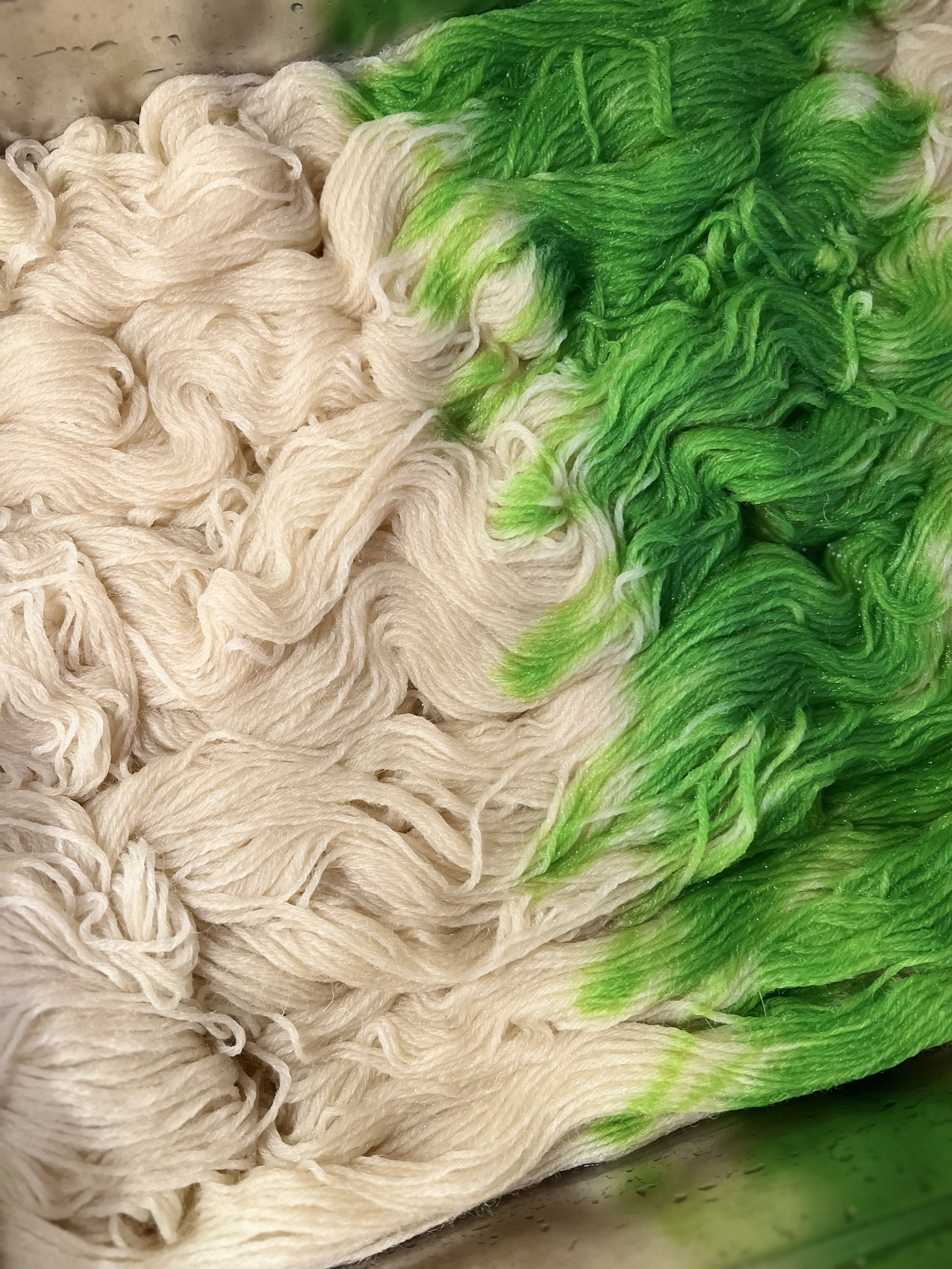 White and green dyed yarns next to each other.