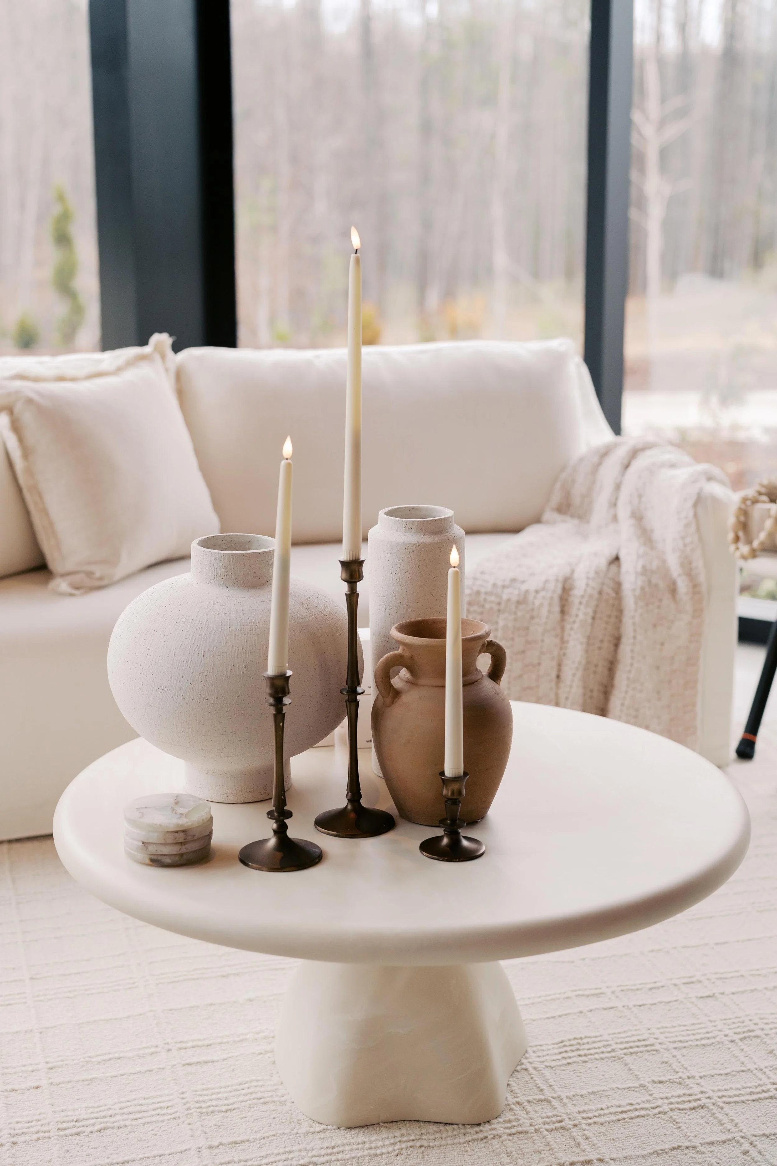 styled coffee table with clay vases, tall bronze candle sticks, and marble coasters