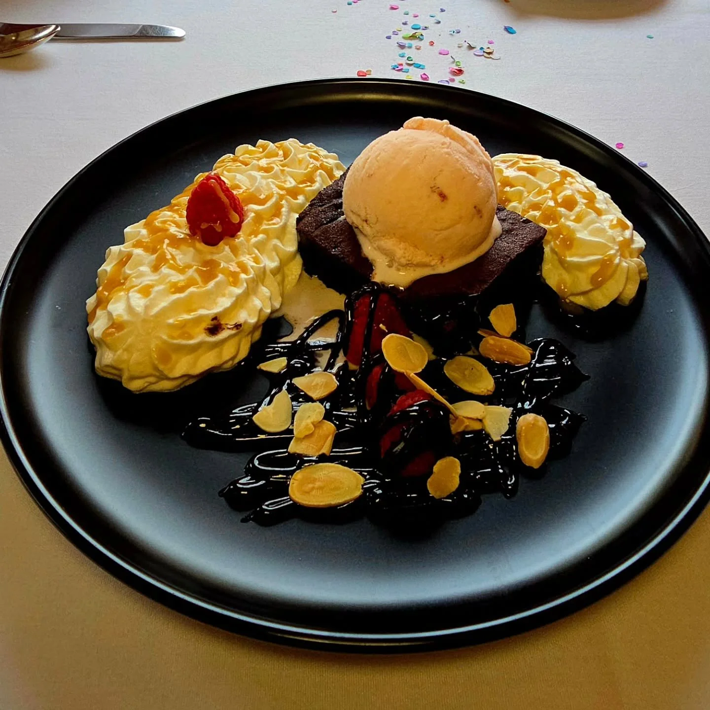 Port wine almost Adulting &quot;Brownie Sundae&quot; on Roids, topped by strawberry ice cream &amp; accompanied by caramel topped whipped cream, raspberries, amaretto chocolate sauce &amp; shaved almonds