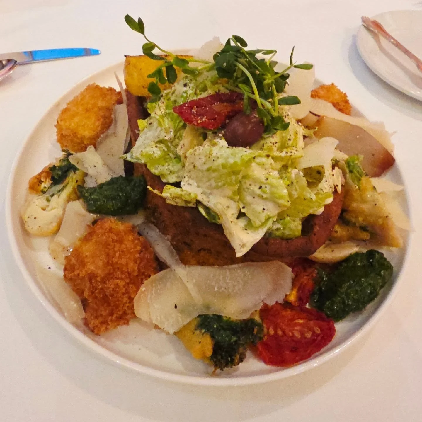 2002 Masochistic Caesar Salad, romaine lettuce, house made dressing tossed in placed in a french baguette crouton ring accompanied by kalamata olives, sundried tomatoes, arugula pesto, tempura fried artichoke stuffed in spinach, jumbo potato croutons
