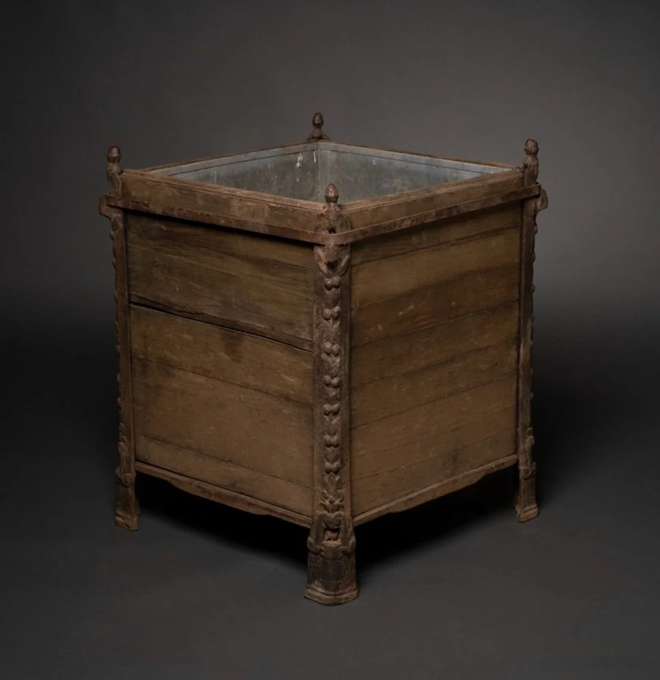 An antique wooden box with carved details on each corner and four legs, against a dark background.