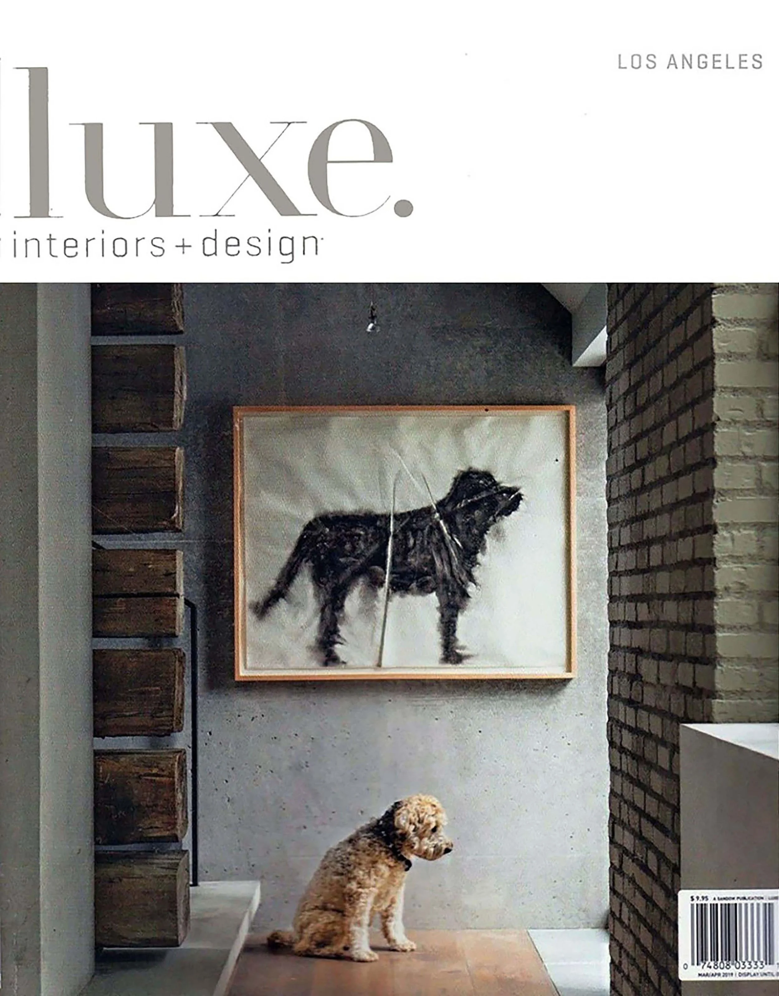 A magazine cover featuring the title 'luxe' with a subtitle 'interiors + design' in Los Angeles. The cover photo shows a small dog sitting on a wooden floor, with a piece of art of a black dog hanging on a concrete wall behind it.