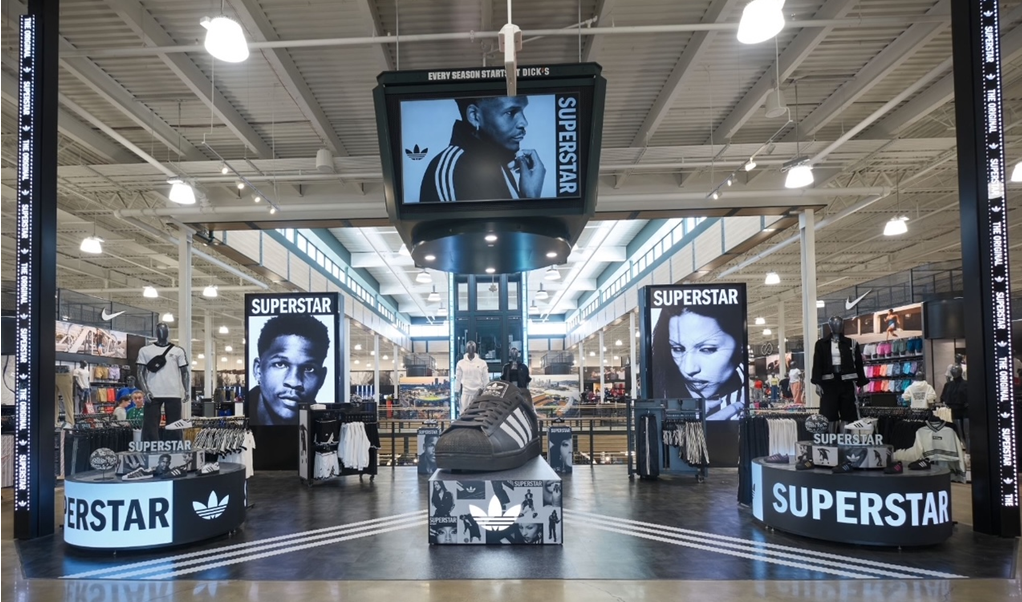 Inside a Nike store featuring Adidas Superstars, with mannequins, clothing, and large posters of celebrities, under bright lighting.