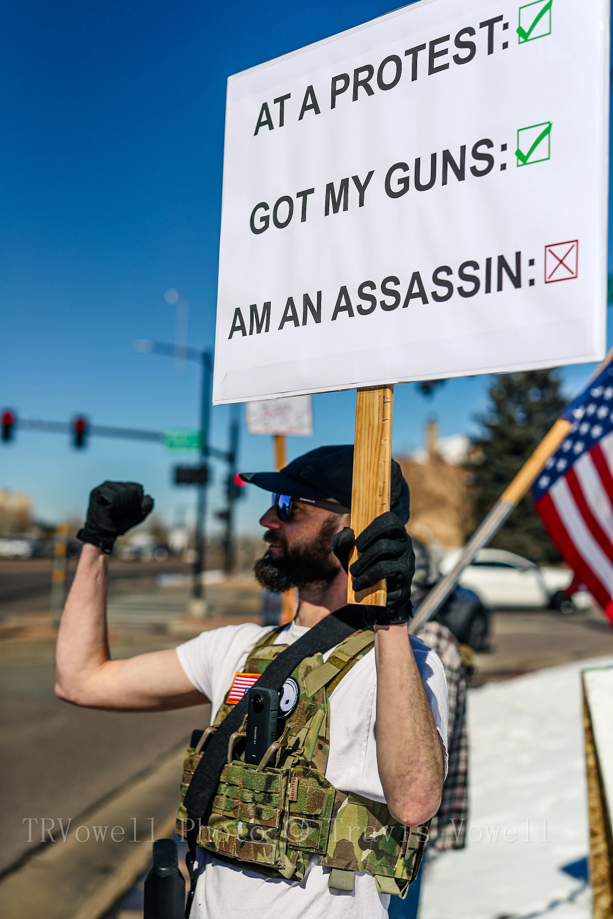 Armed protester holds an At a Protest Got My Guns sign in Littleton, Colorado.