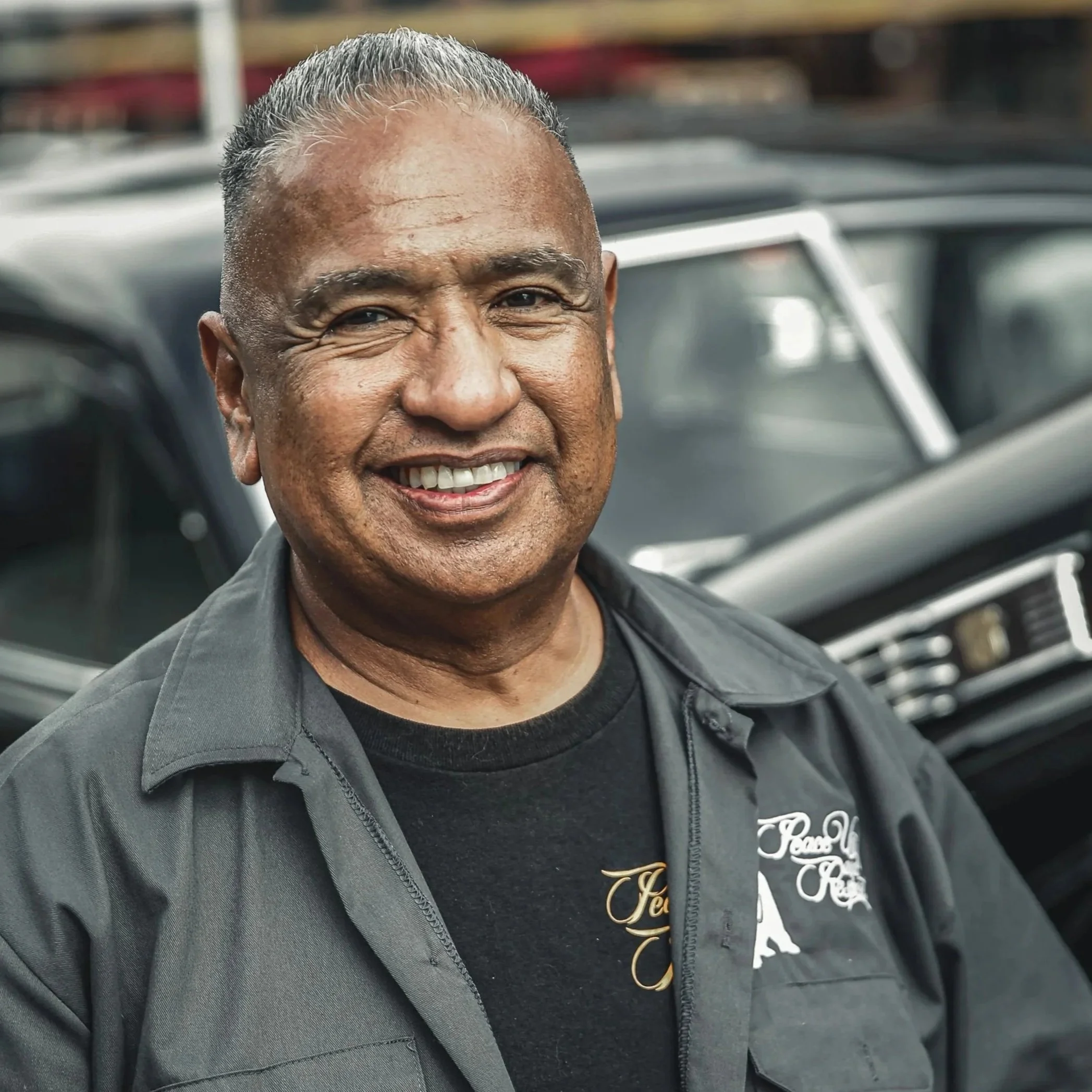 Outdoor portrait of a smiling man standing beside a classic car in Denver.