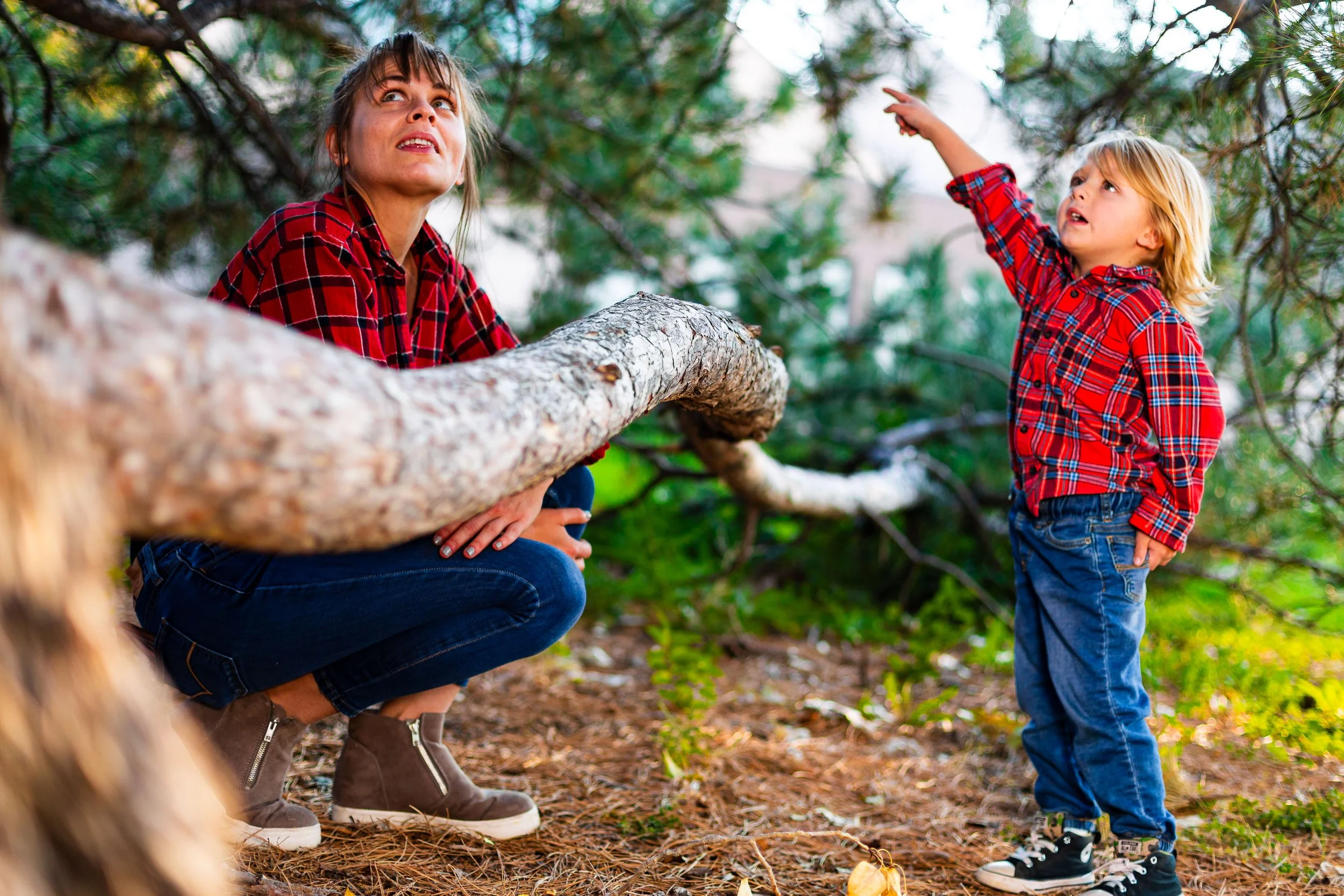 Mother and son interact beside a tree during an outdoor family photo session.