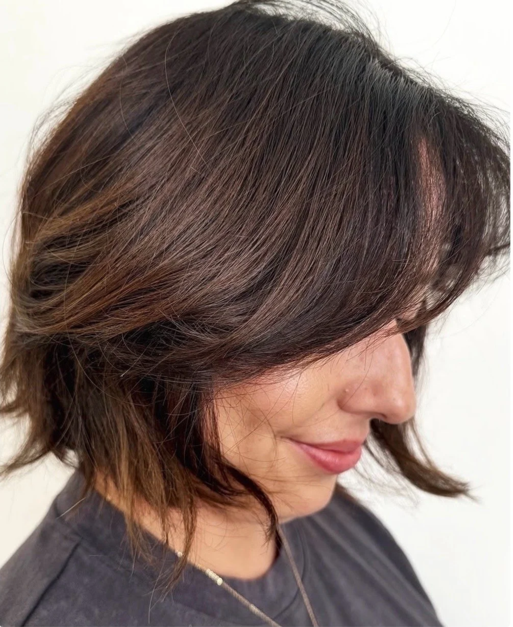 A client showcasing a precision textured brunette bob haircut with curtain bangs from the haircutting specialists at Little Saint Salon