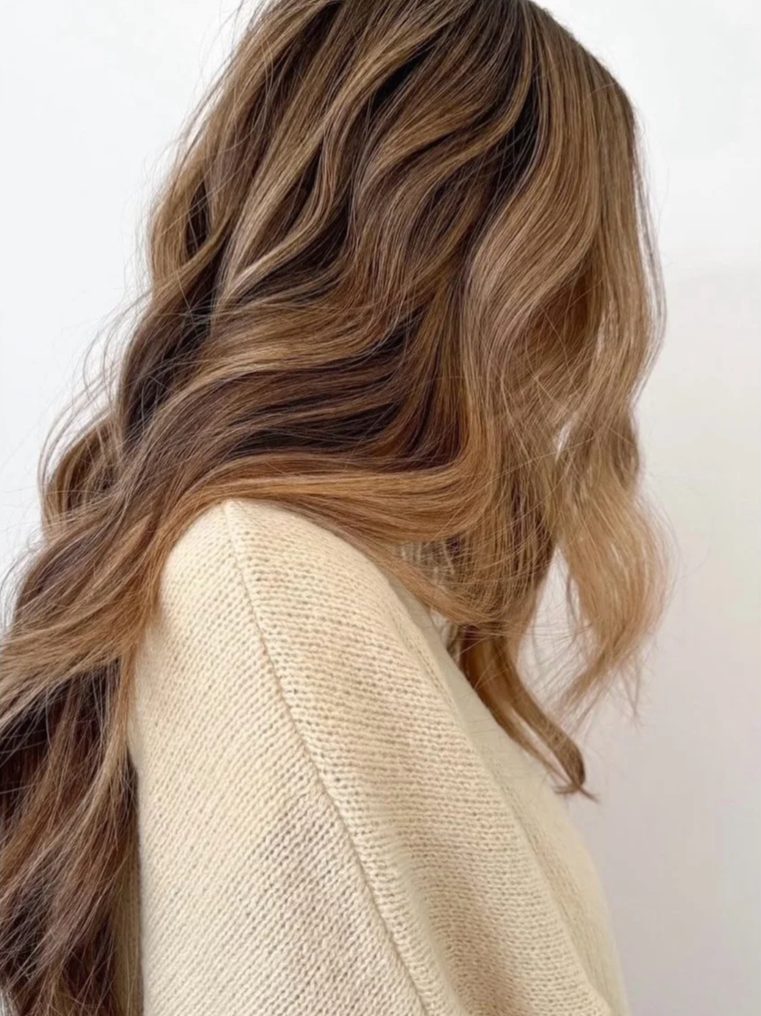 A client with long, wavy hair showcasing a soft lived-in honey blonde color service at Little Saint Salon in NE Portland