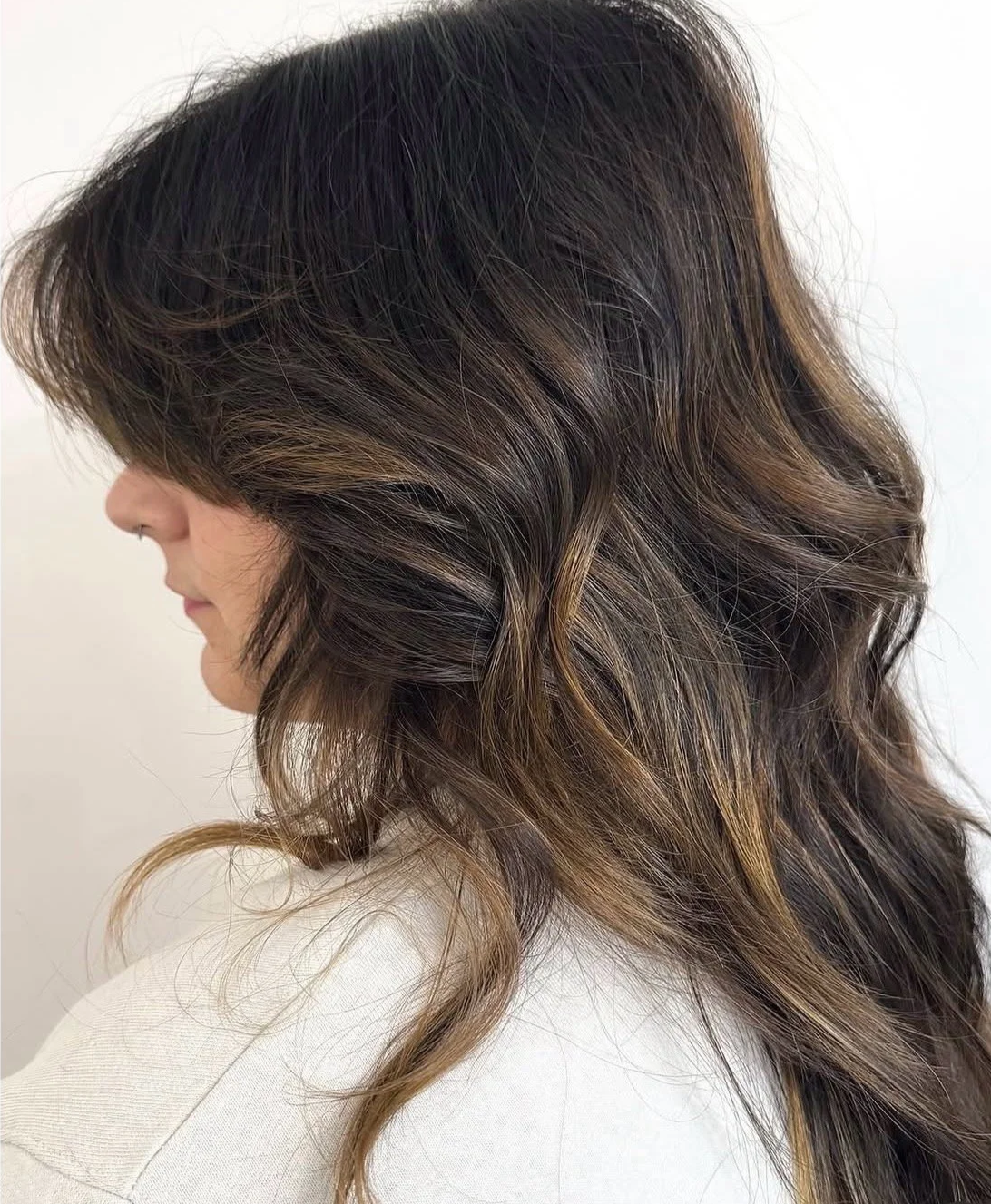 A side view of a client with long soft layers and a voluminous blowout, highlighting a custom haircut at Little Saint Salon in Portland
