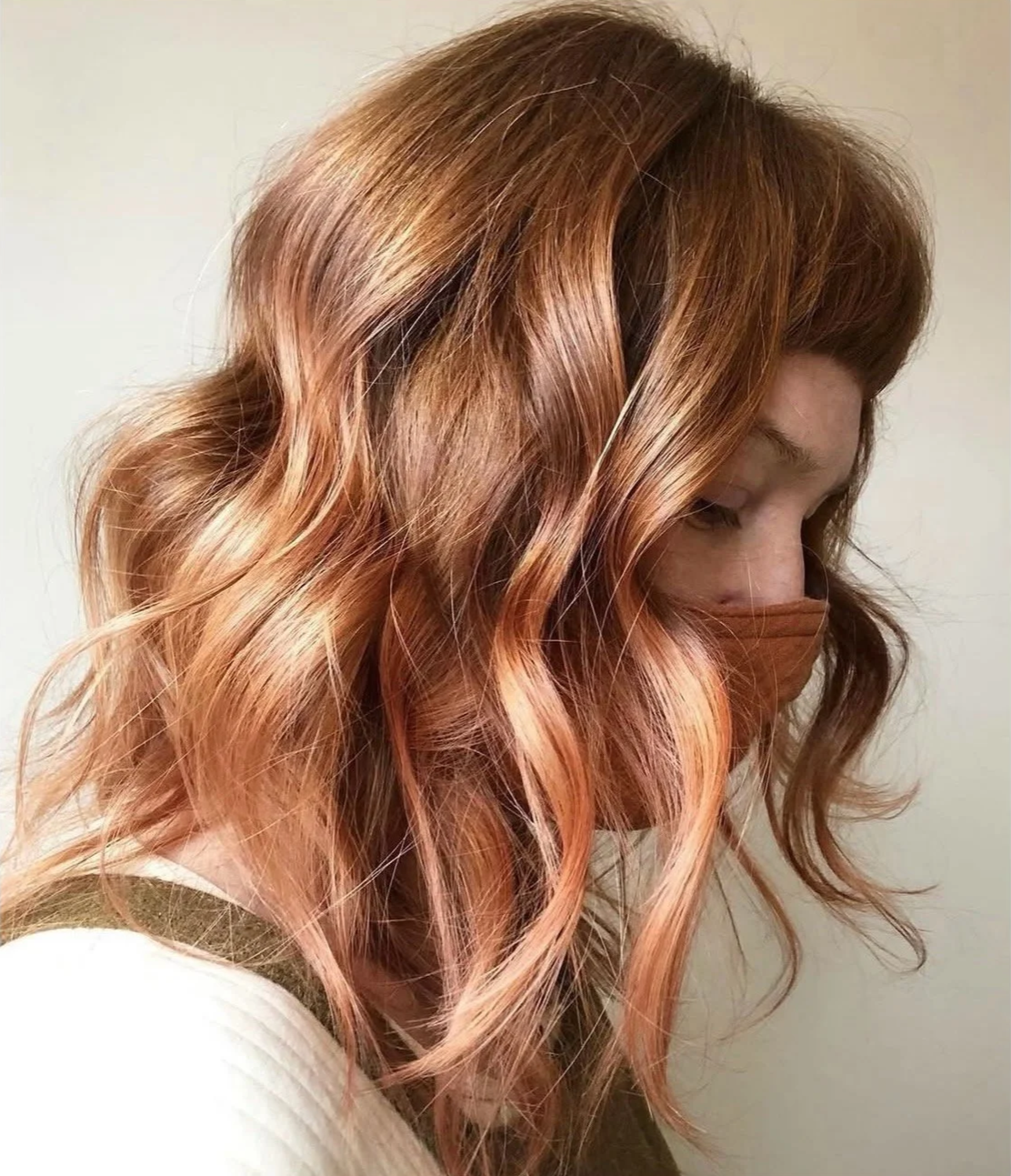 A client with a dimensional rose gold and copper balayage hairstyle featuring soft waves, styled at Little Saint Salon in NE Portland