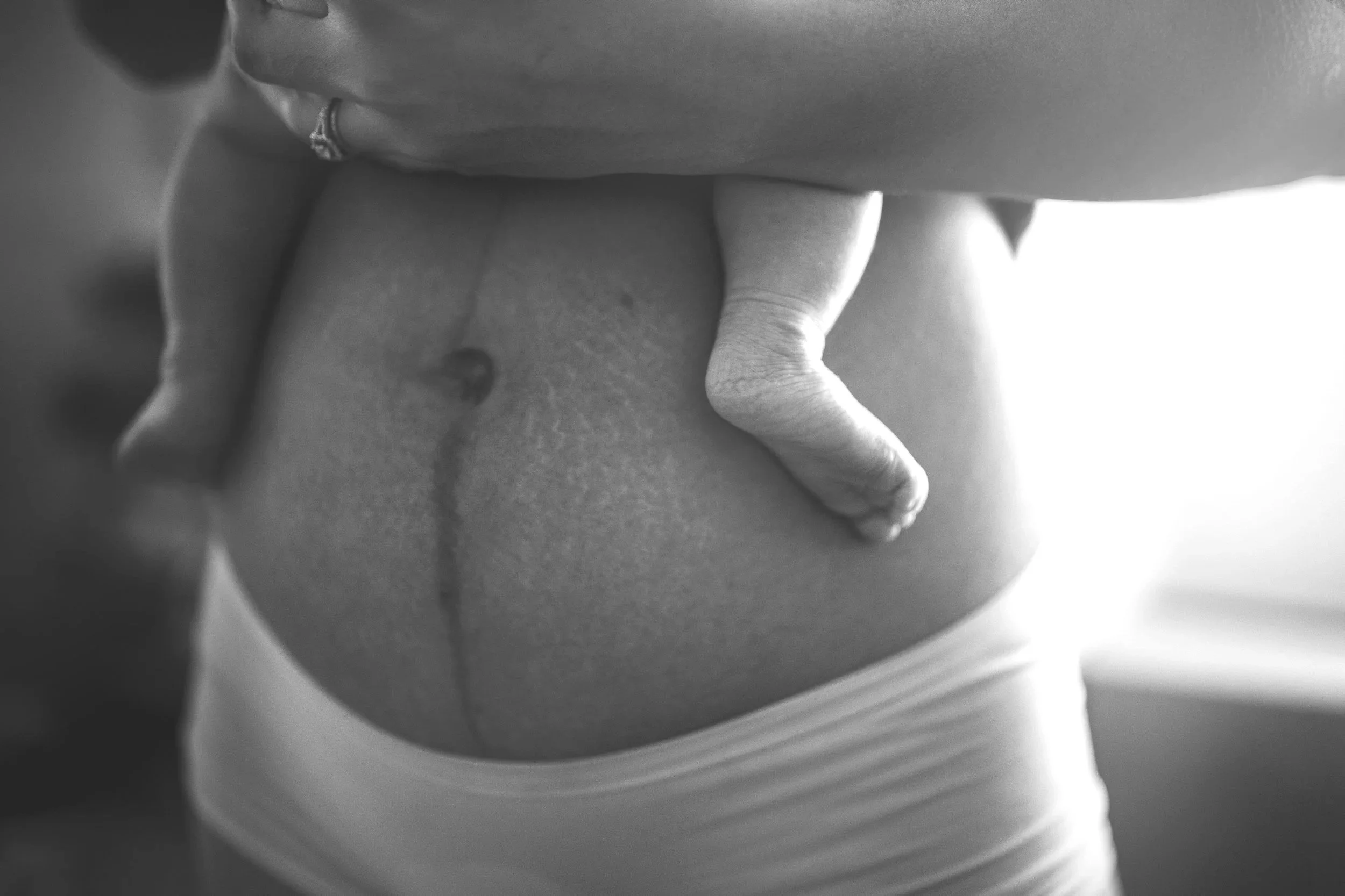 Postpartum woman holding baby for postnatal massage.