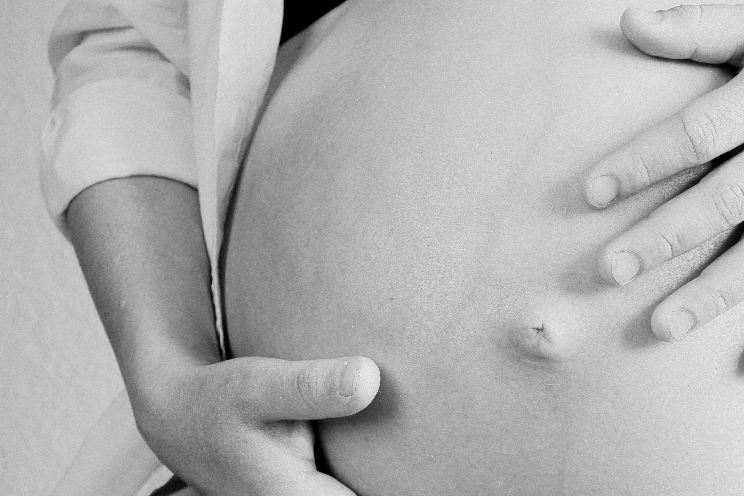 Pregnant woman holding belly for prenatal massage.