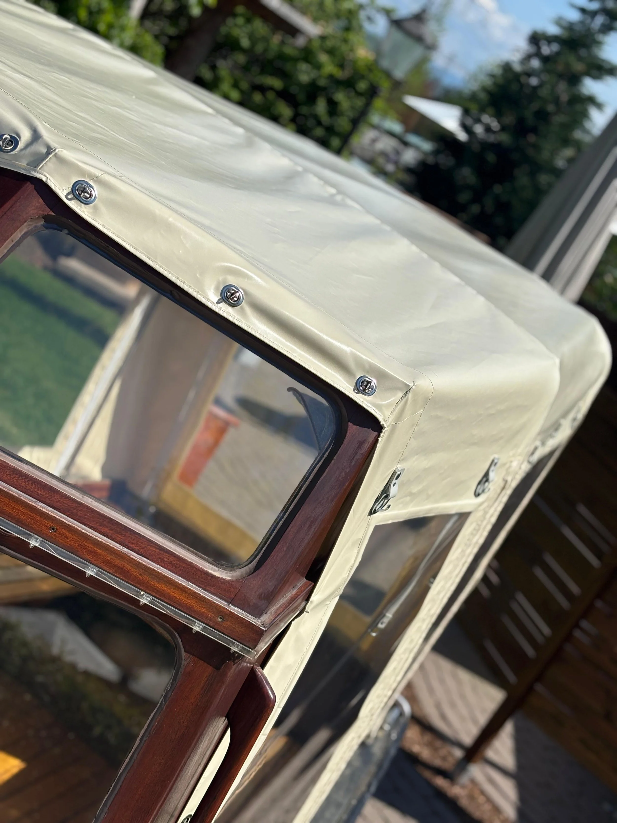 Nahaufnahme eines Gummizugsystems und einer Holzrahmenverkleidung an einem vintage Wohnmobil oder Boots, aufgenommen im Freien.