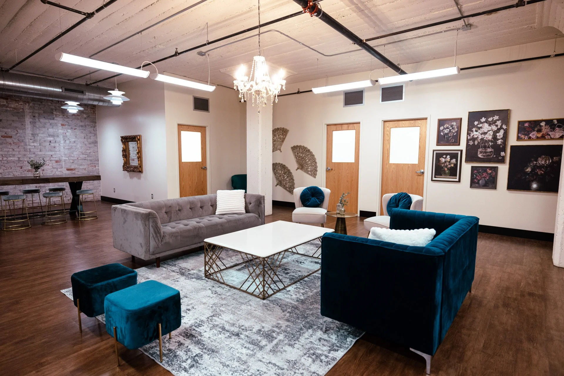 White wedding dress hanging on a white hanger with the name 'Mesa Logansia' written on it, against a wall with floral still life paintings.
