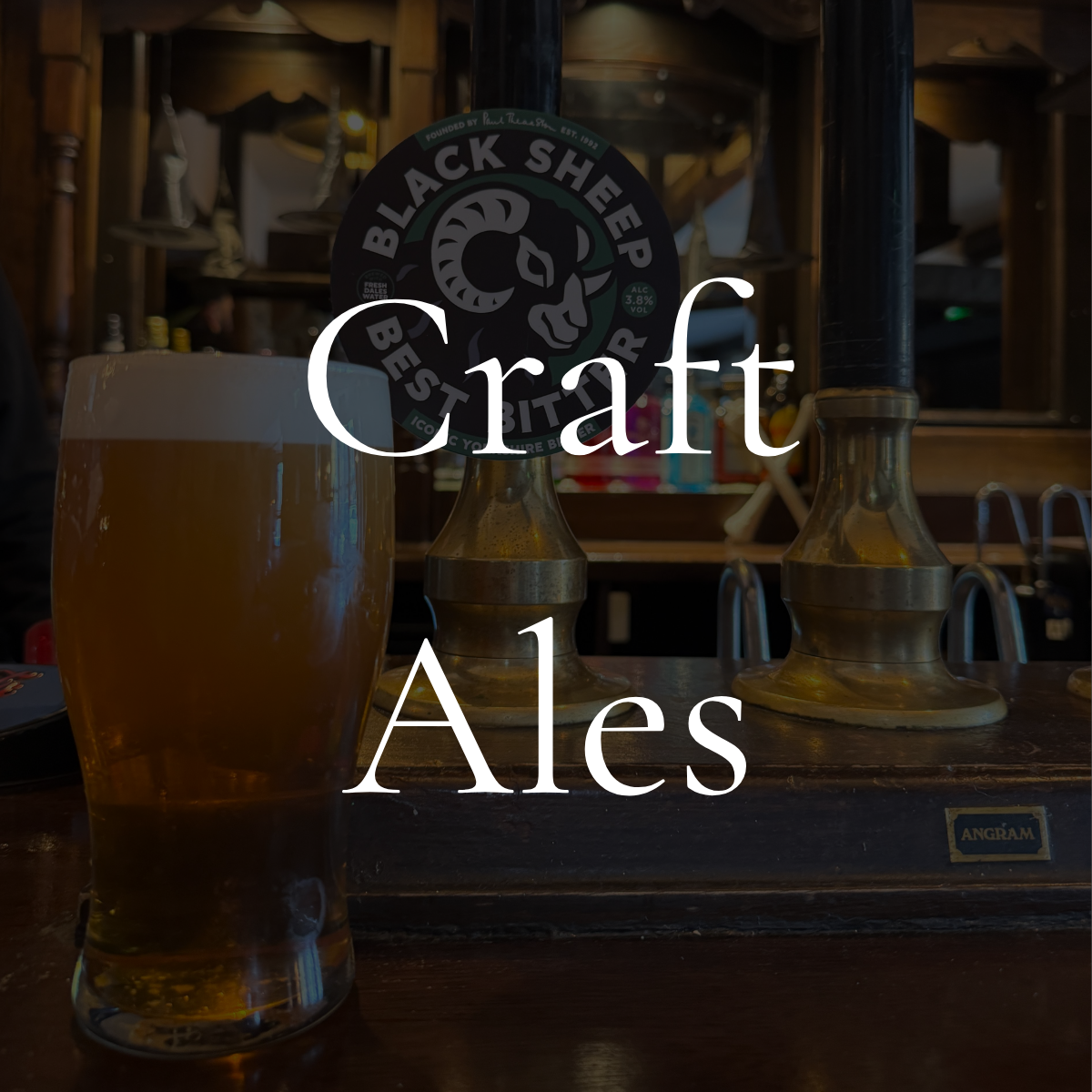 A glass of beer on a wooden bar counter with a Black Sheep Brewing logo and beer tap handles in the background.