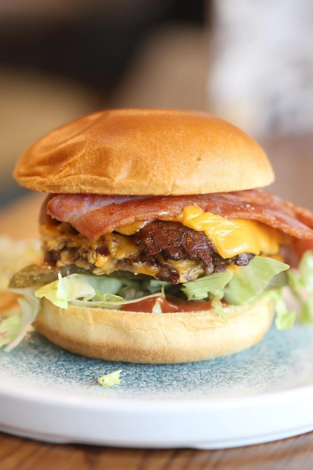 Close-up of a cheeseburger with bacon, lettuce, tomato, and melted cheese on a bun.