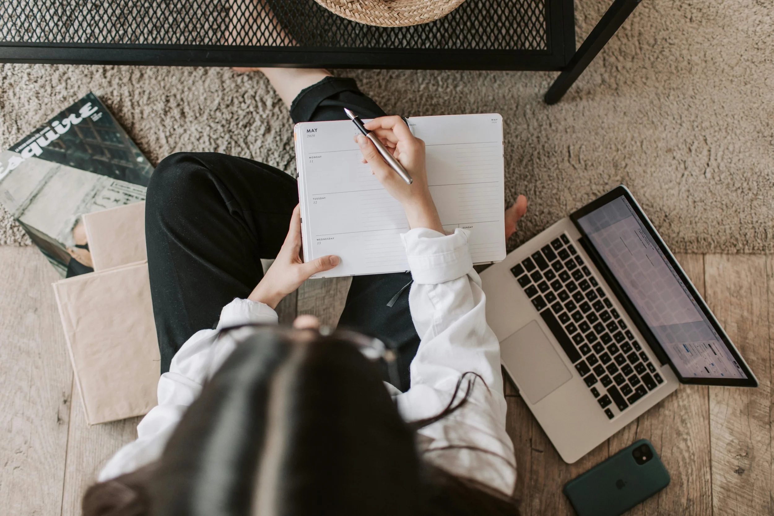 girl sitting on the floor with books, laptop, and a journal