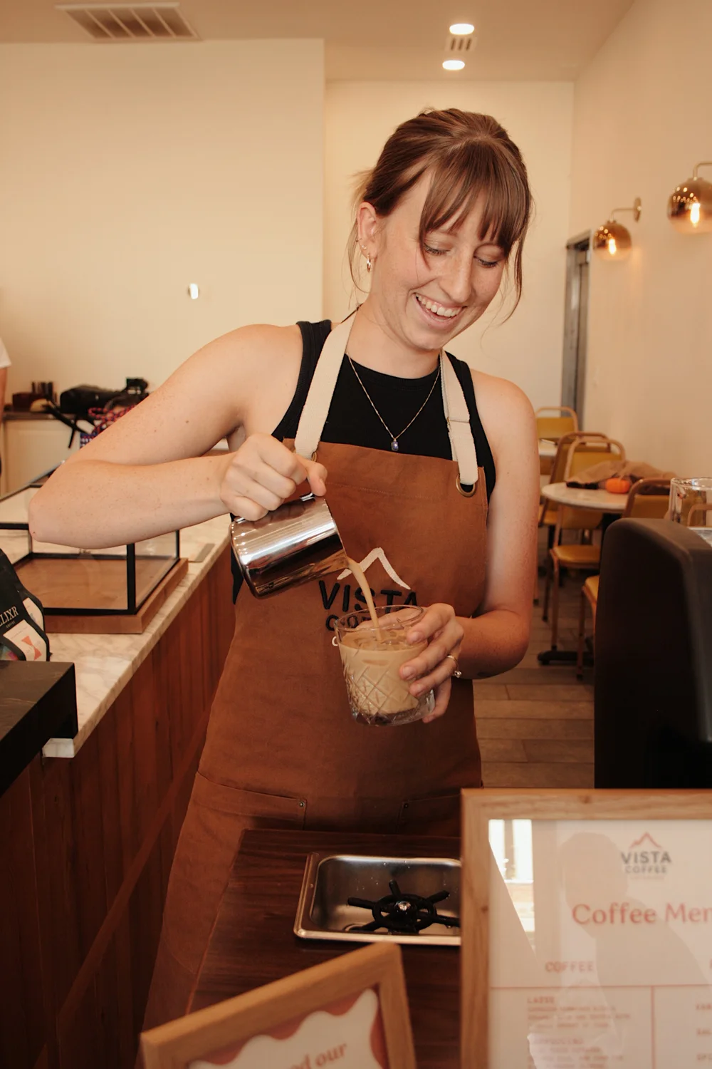 Barista pouring milk into an iced latte at a catered event