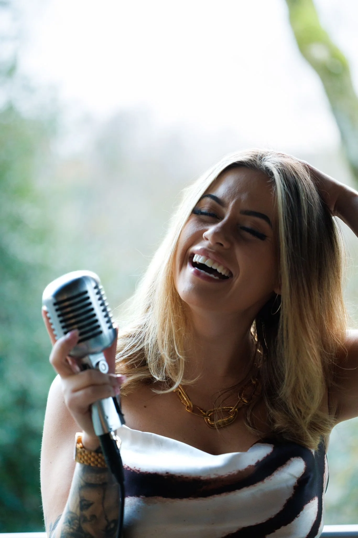 A UK Wedding Singer, Britt, with blonde hair singing or speaking into a vintage microphone, smiling and enjoying herself. 
Liverpool based Wedding Singer. UK Wedding Singer
Drinks Reception Singer, Ceremony Singer. Live Music at Weddings.