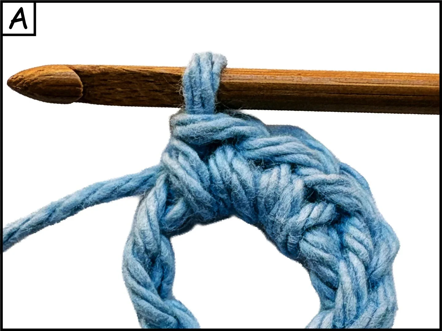 A close-up of a wooden stick with a blue yarn looped and tied around it, forming a knot.