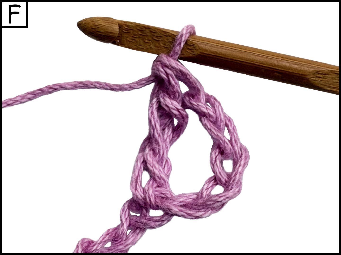 Close-up of a pink yarn looped around a wooden crochet hook, with a plain white background.