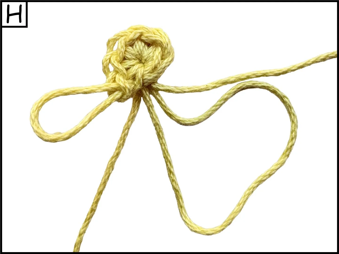 Yellow rope tied in a knot with a loose end forming a heart shape on a white background.