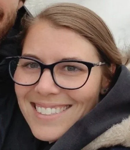 Close-up of a smiling woman with glasses and blonde hair.