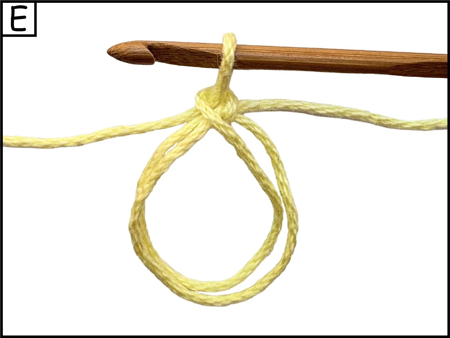 A wooden crochet hook with a yellow yarn looped around it, forming a knot in the yarn.