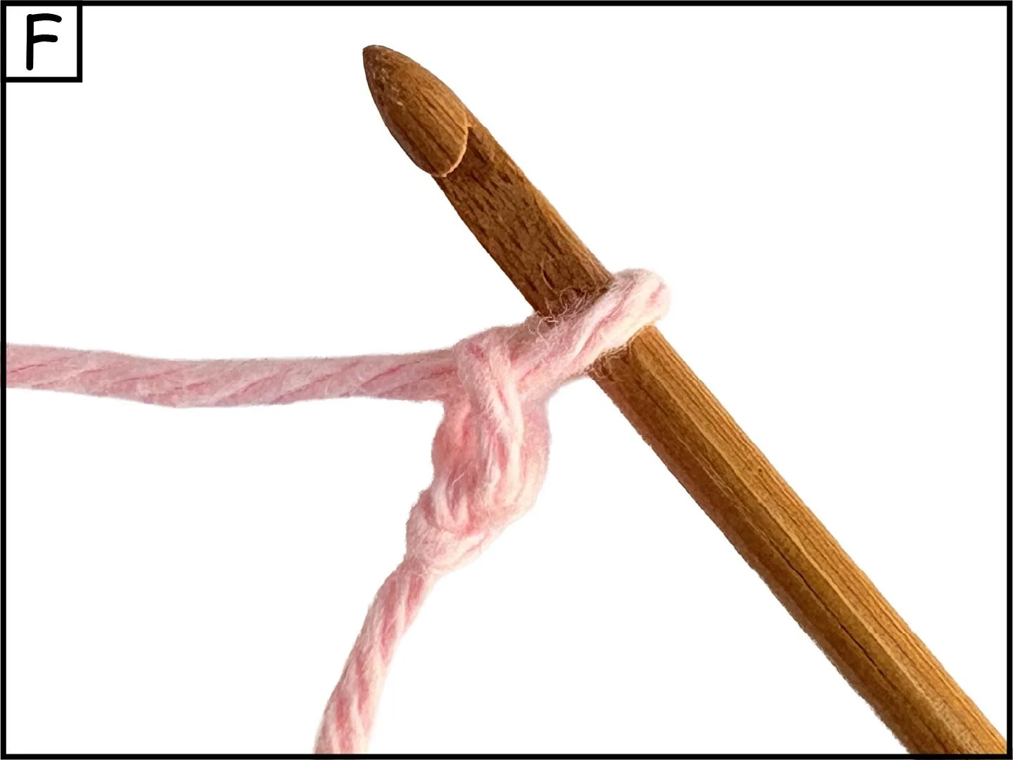 A crochet hook passing through a pink yarn tied in a knot.