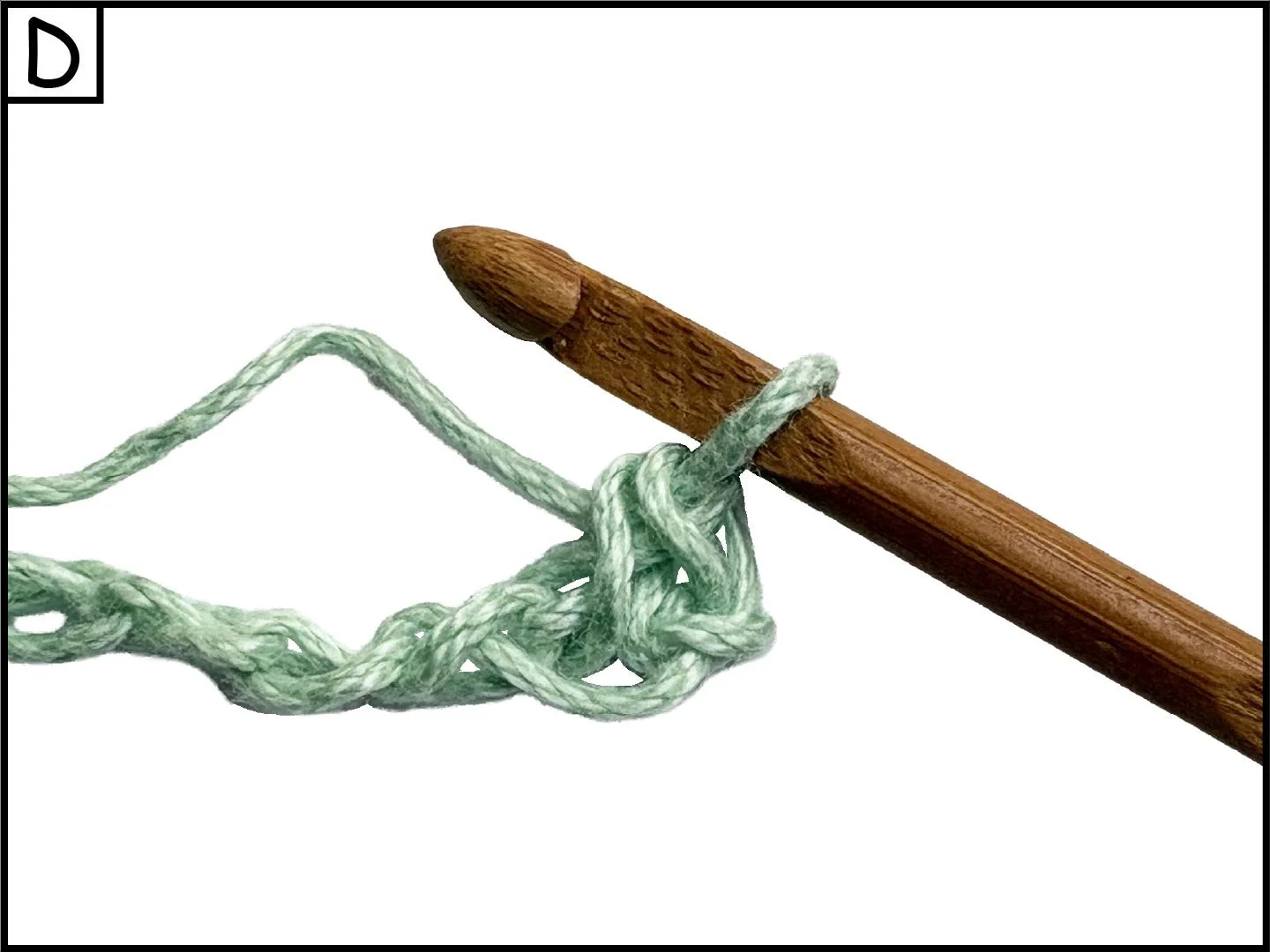 A wooden crochet hook pulling a green and white yarn through a loop.