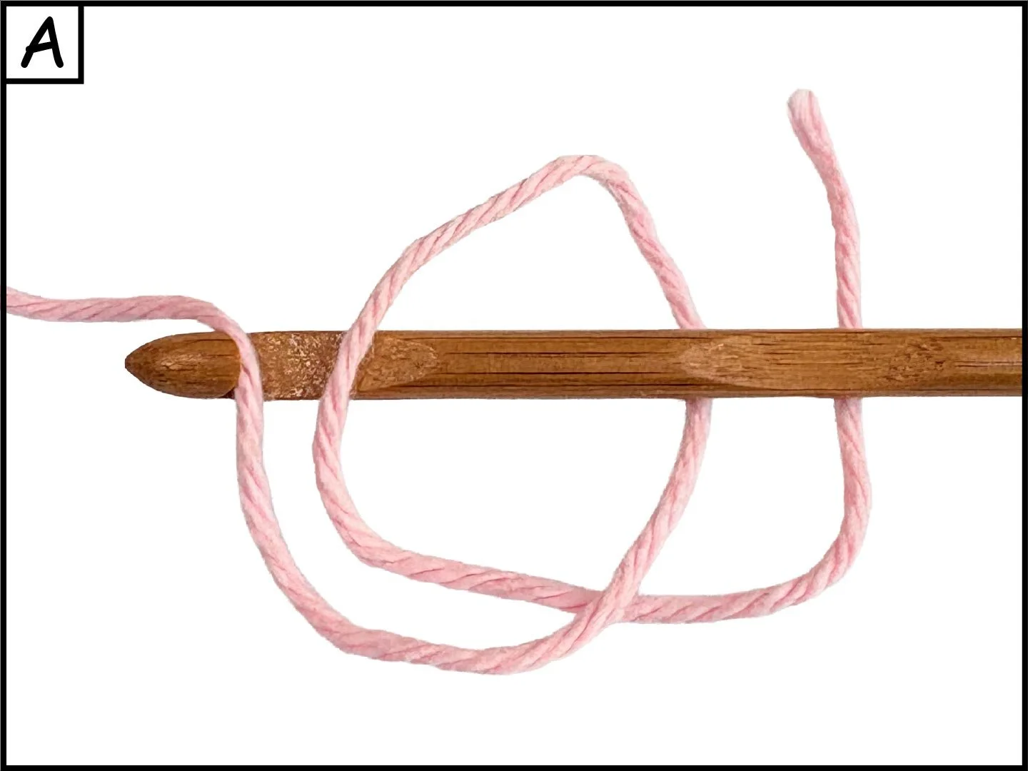 A wooden knitting needle with pink yarn looped around it against a white background.