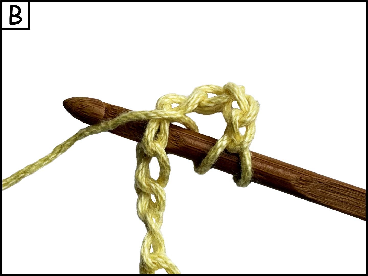 A wooden crochet hook with a yellow yarn looped around it, set against a white background.