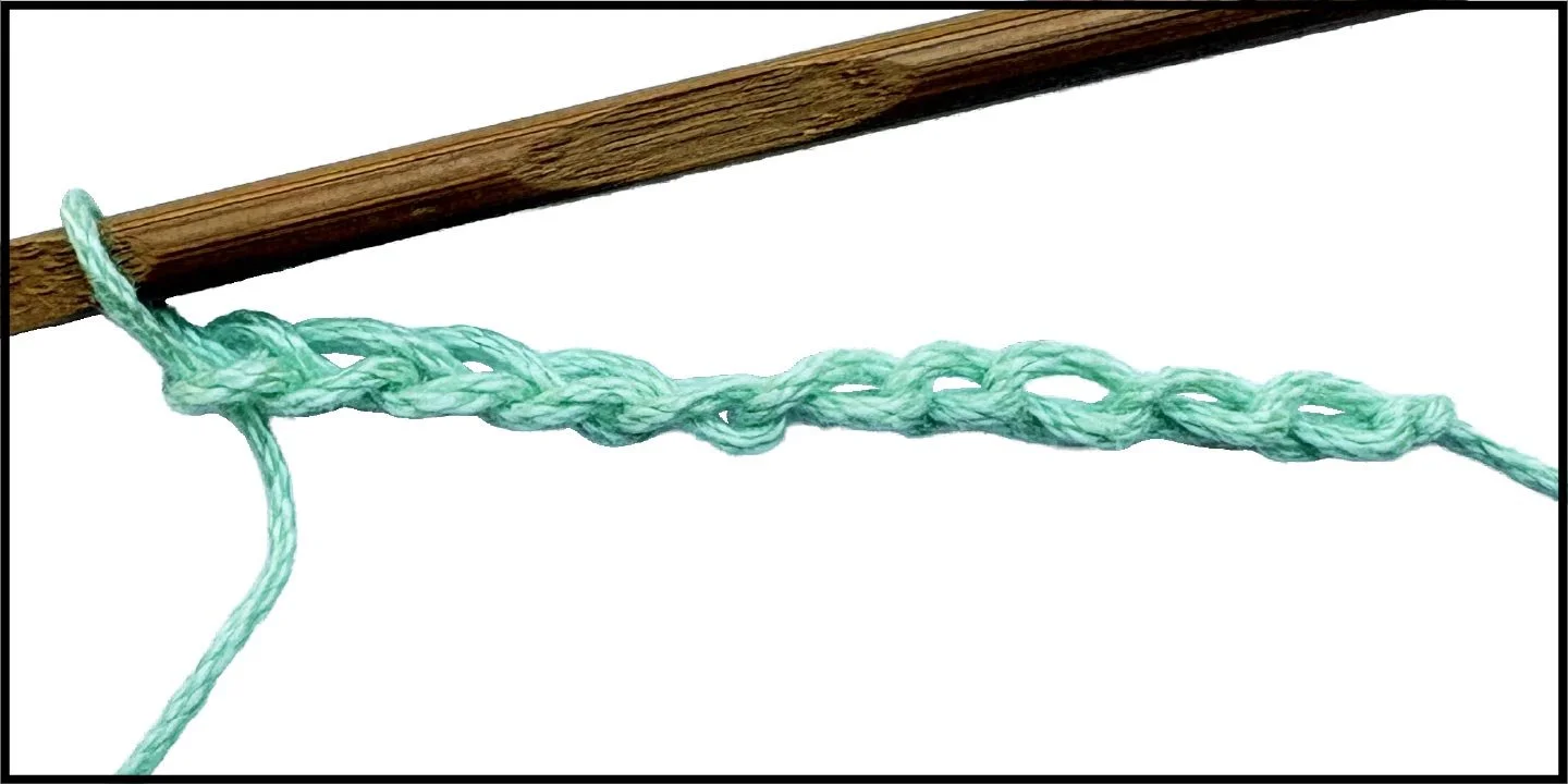 A close-up of a twisted green yarn tied around a wooden stick.