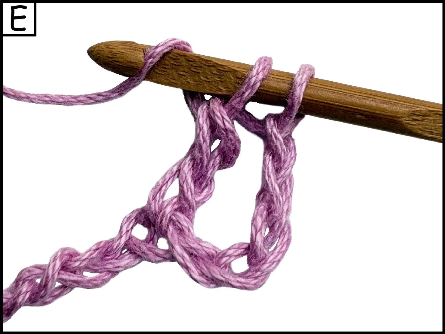 A wooden crochet hook with pink yarn looped around it, forming a small loose knit hanging from the hook.