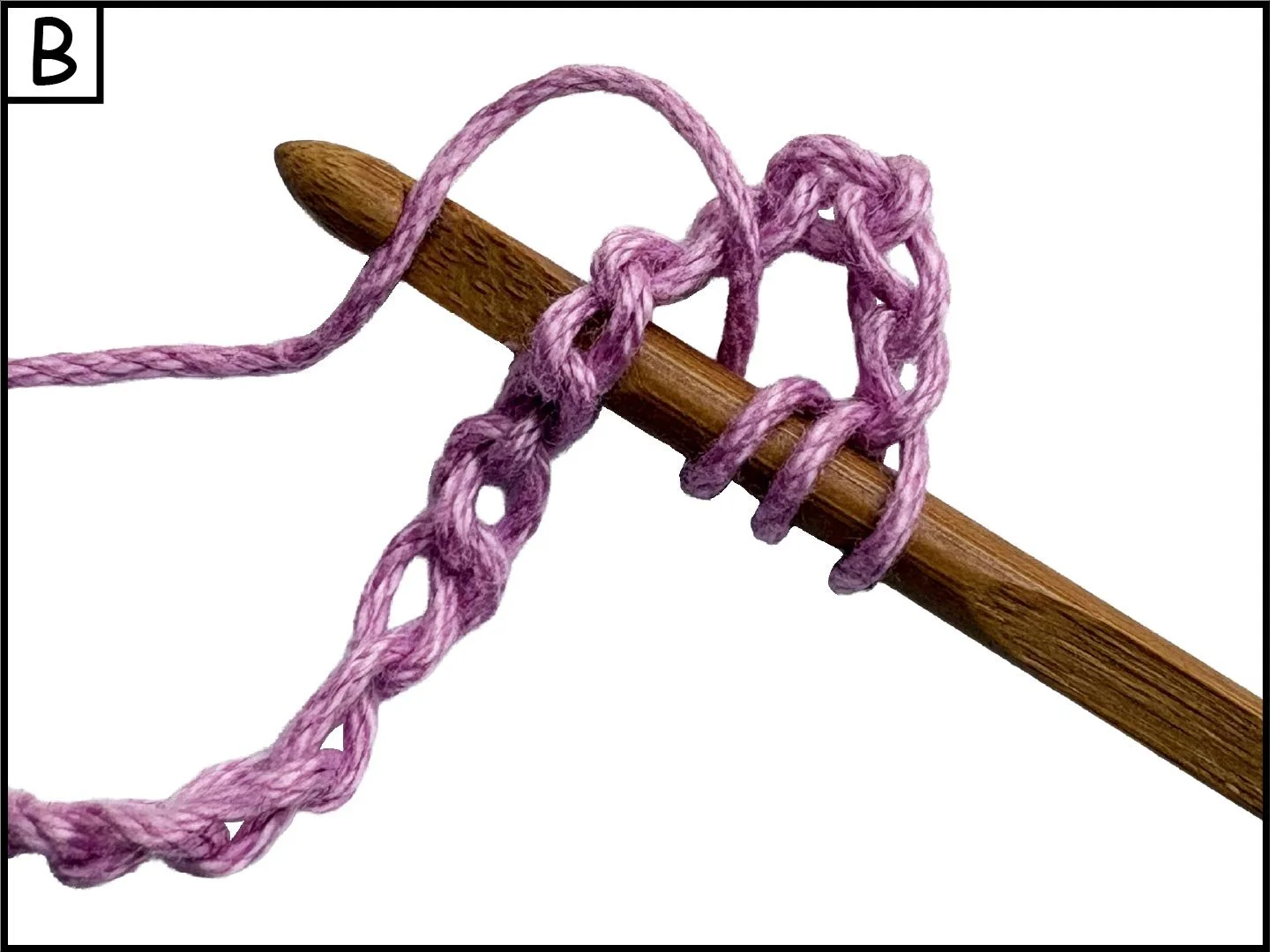 Close-up of a wooden crochet hook with pink yarn wrapped around it, partially crocheted.