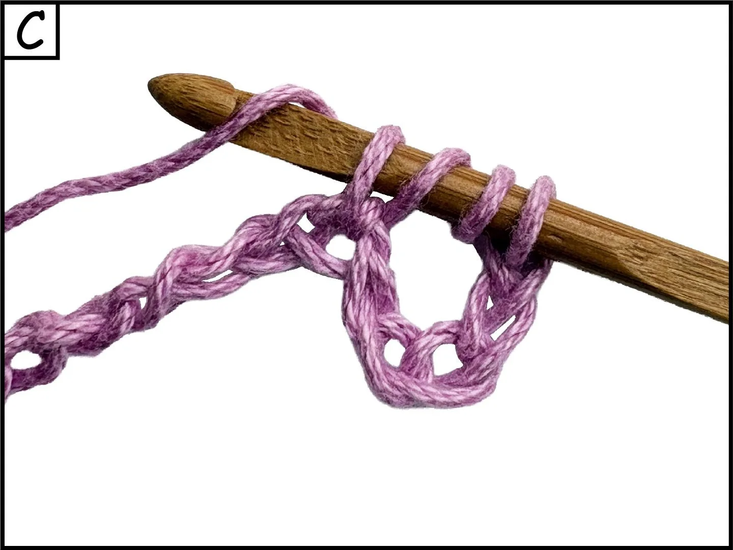 A wooden crochet hook with pink yarn wrapped around it, forming a loop.