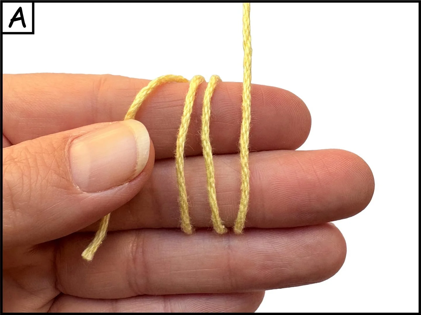 A close-up of a person's hand holding a yellow yarn wrapped around the fingers, with some yarn hanging down.