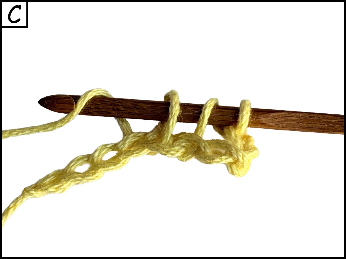 A wooden knitting needle with yellow yarn looped around it, depicted in the process of knitting.