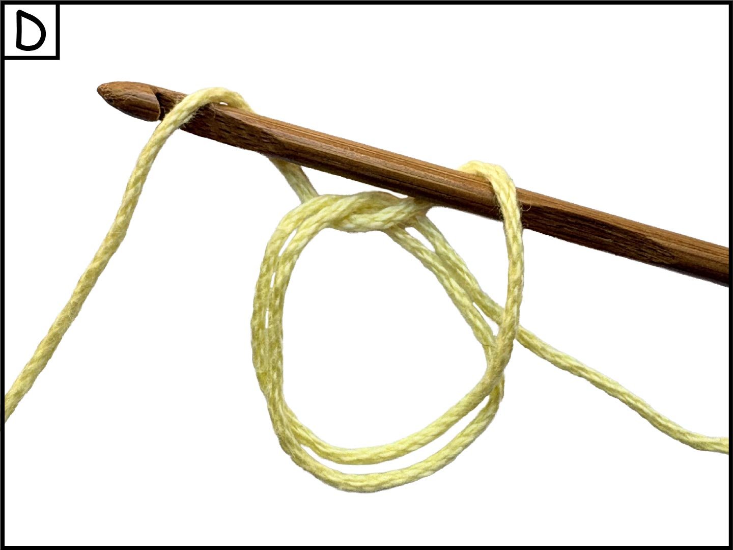 A wooden knitting needle with a loop of yellow yarn, with part of the yarn wrapped around the needle, on a white background.