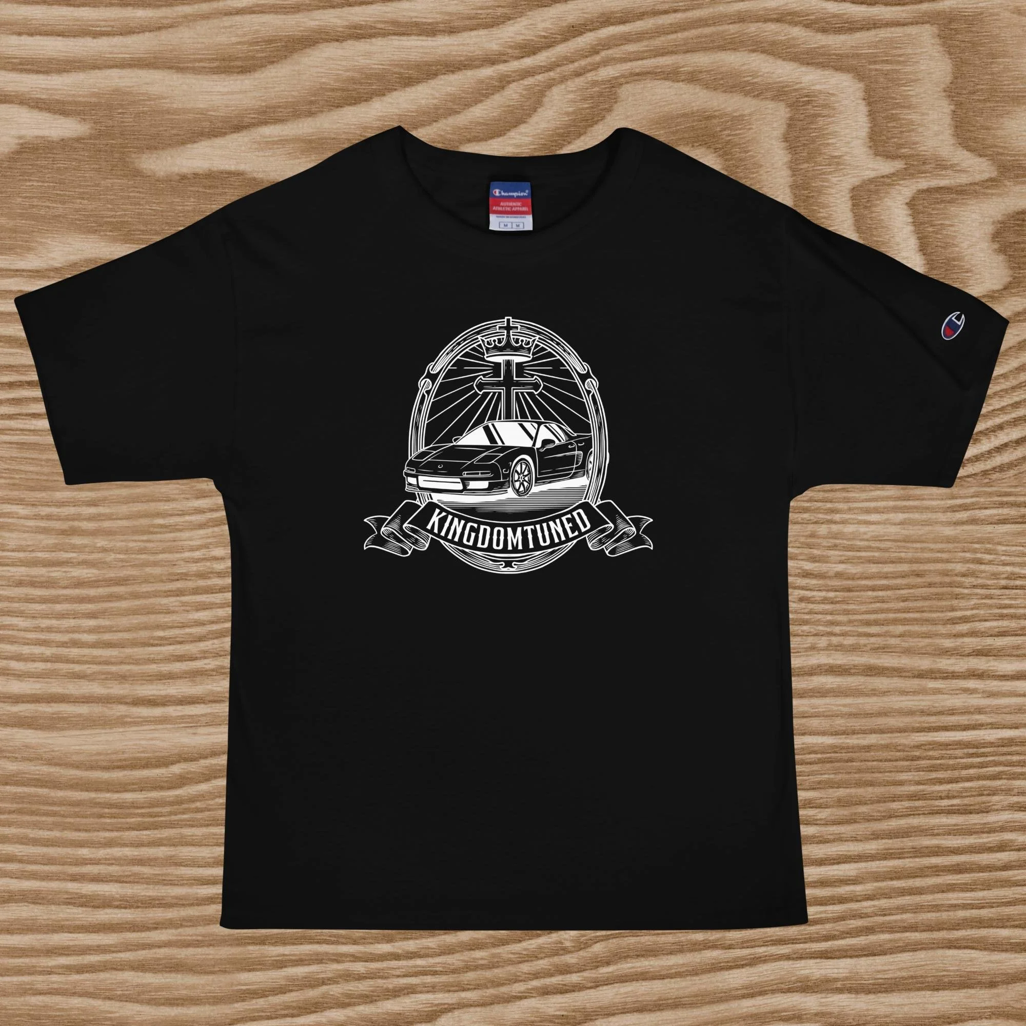 Black T-shirt with a white graphic design of a sports car, a cross, and a crown, with a banner reading 'KINGDOM TUNED' underneath.