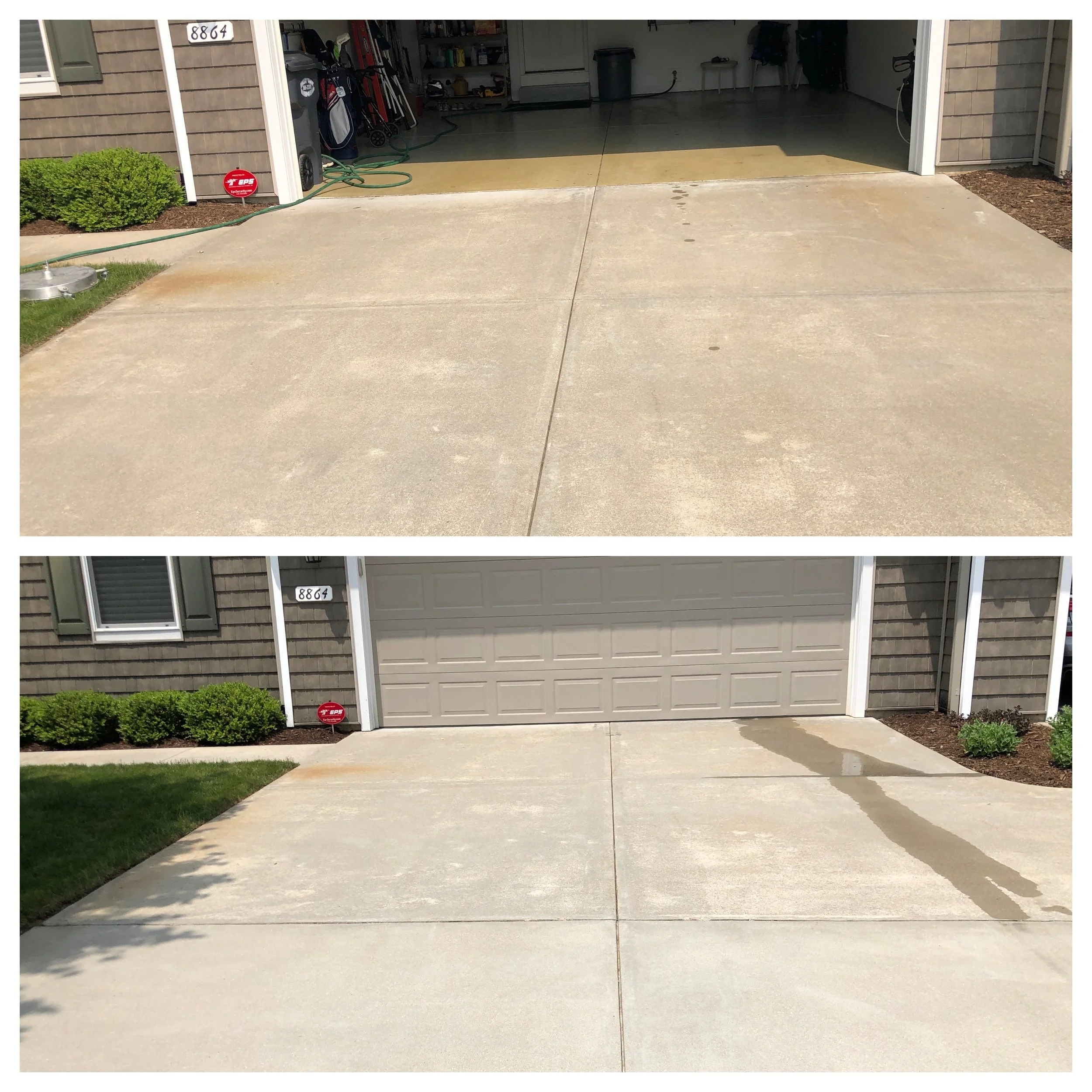 A residential garage with an open door showing the interior organized with tools and lawn equipment, surrounded by a concrete driveway, some grass, and landscaped bushes.