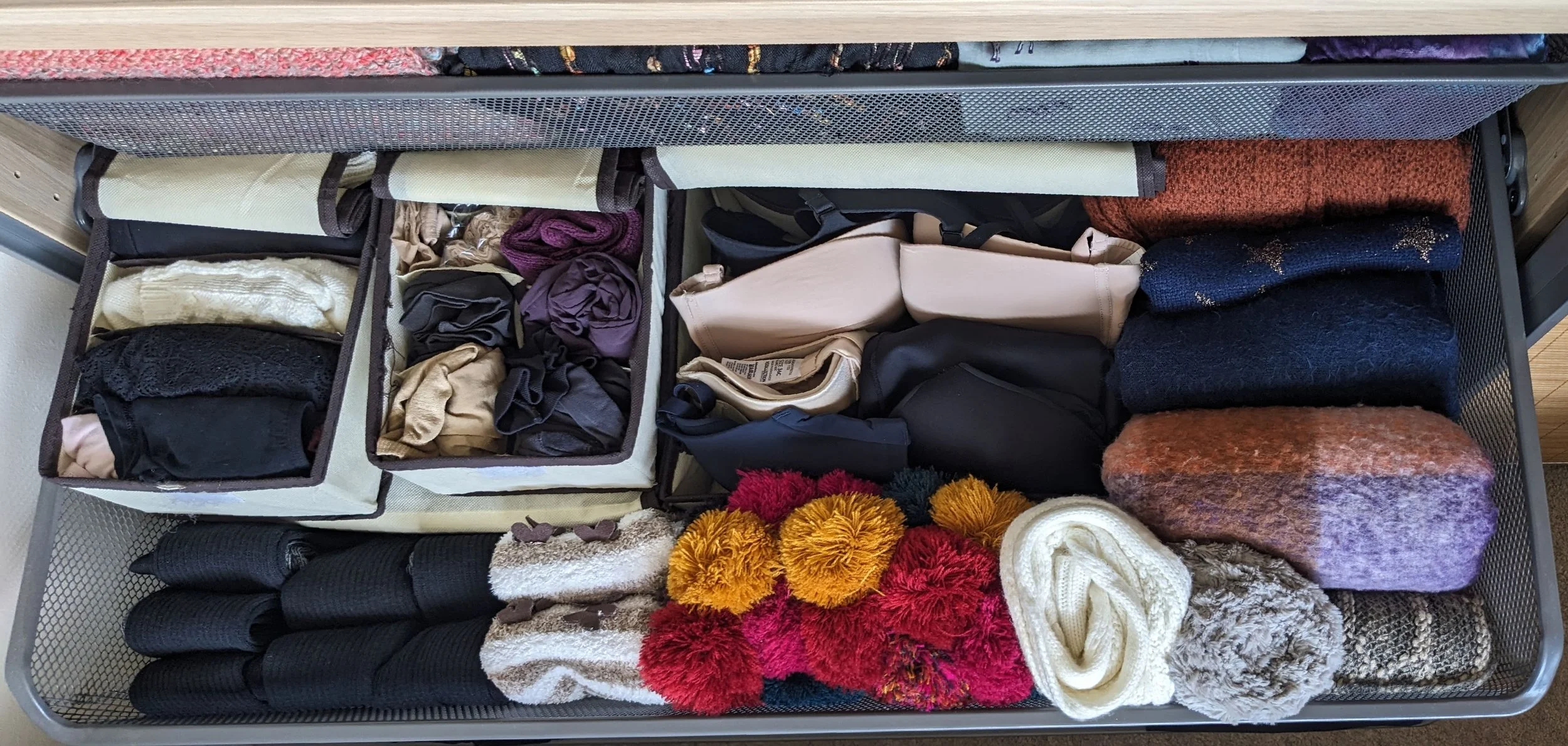 Organized drawer containing folded clothes, including socks, scarves, and sweaters.