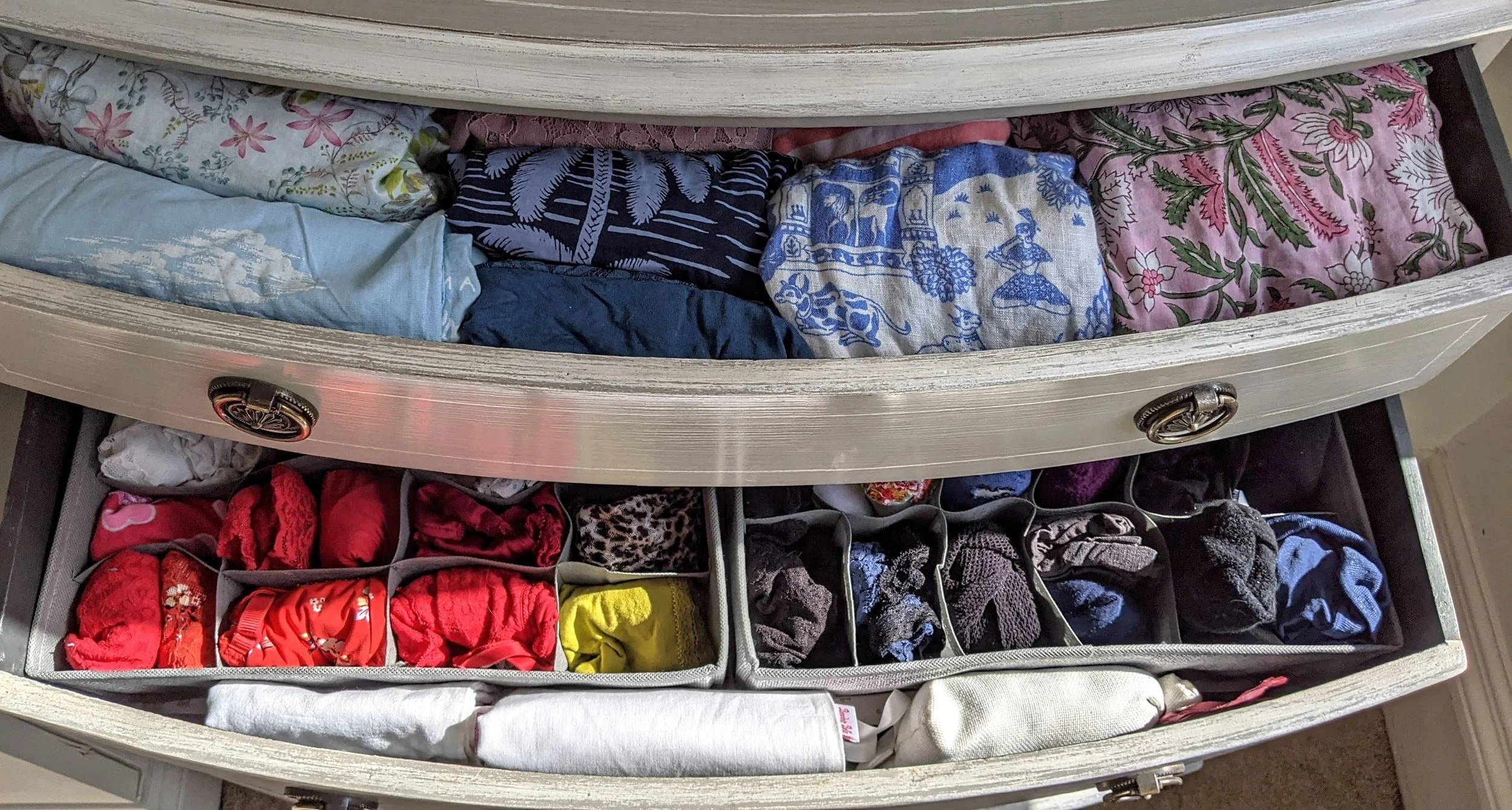 Open dresser drawer with neatly folded underwear and socks organized in divided compartments.