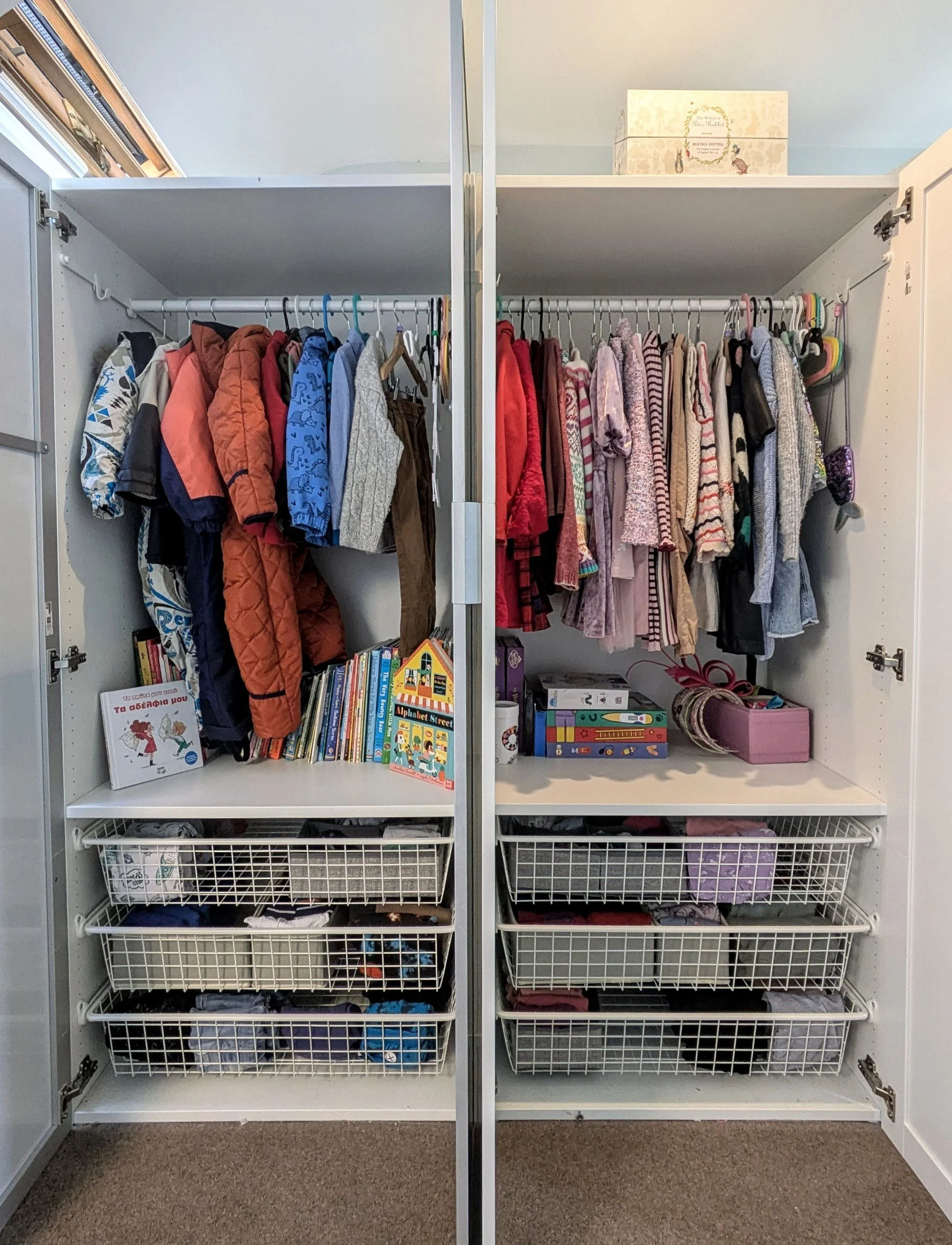 Open wardrobes filled with children's clothes, books, and storage bins.