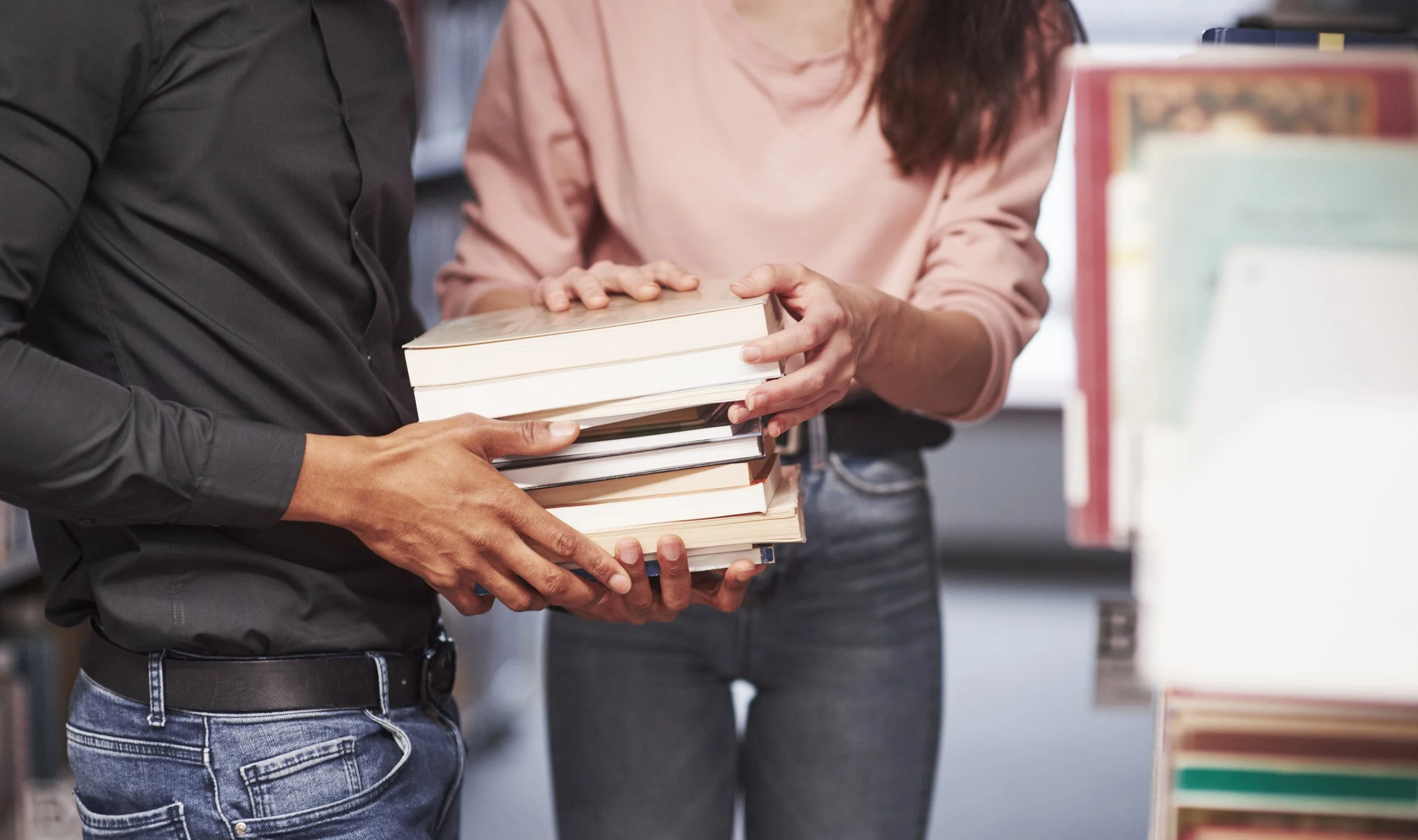 Deux personnes échangeant un lot de livres dans une librairie.